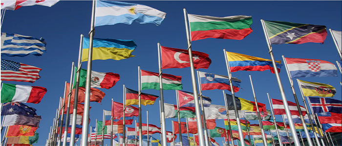 Image of the flags of the World on flag poles against a blue sky background