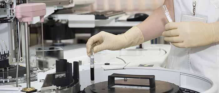 Image of a scientist placing a sample in test tubes in a laboratory