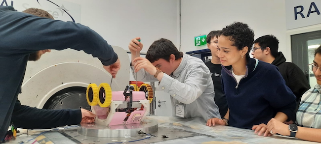 A UKSEDS staff member, Eric Dawe, Phoenix Nelson, and Reya are at the front of the table, with Shuo Feng and Zlatan Čeljo standing at the back