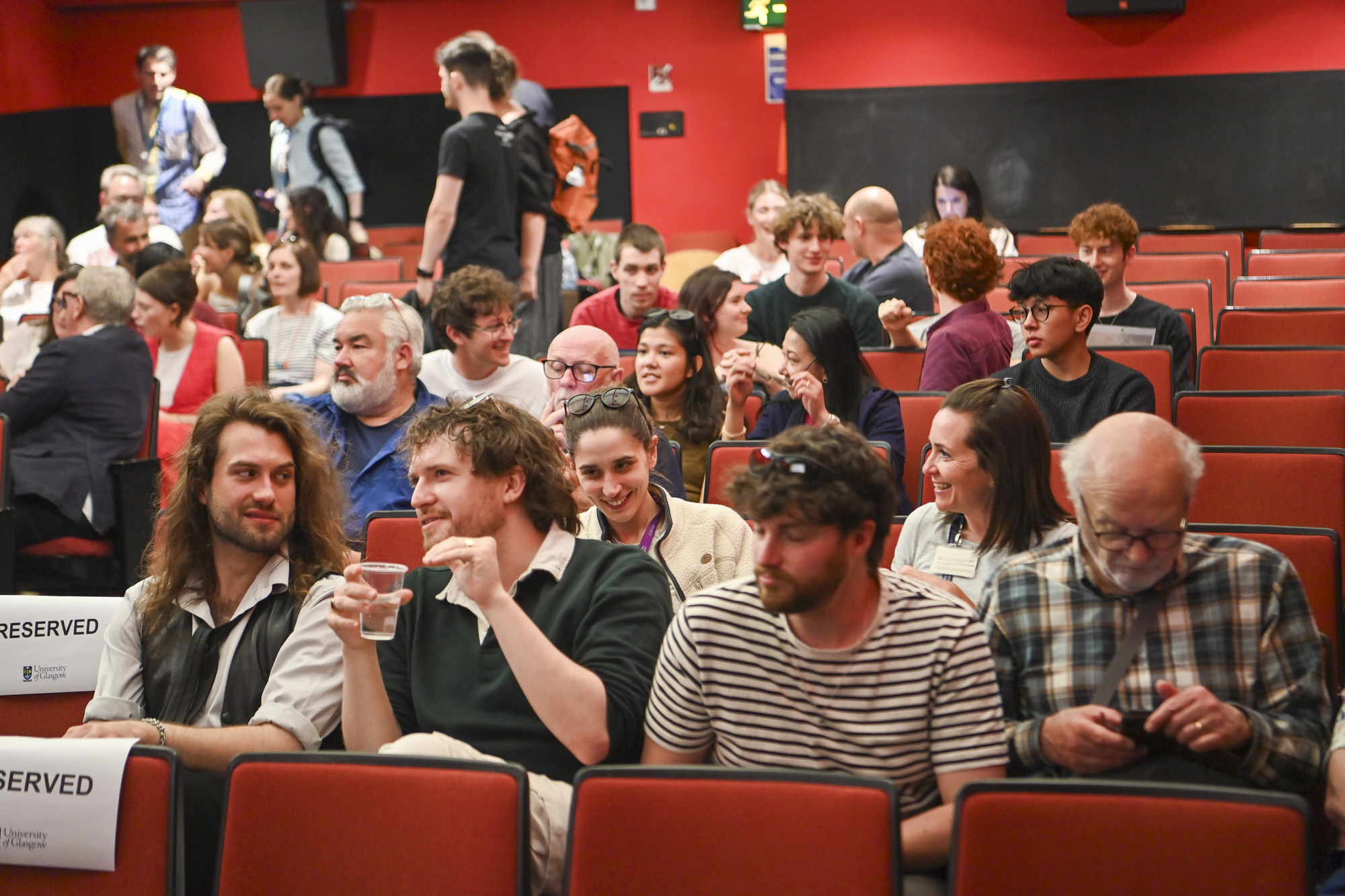a large group of staff, students and participants sitting in the Andrew Stewart Cinema speaking