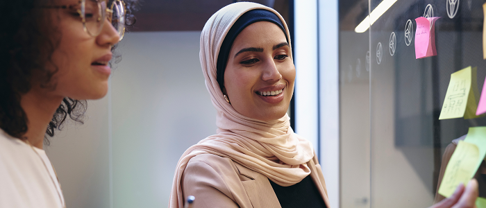 Two people placing post it notes on a wall