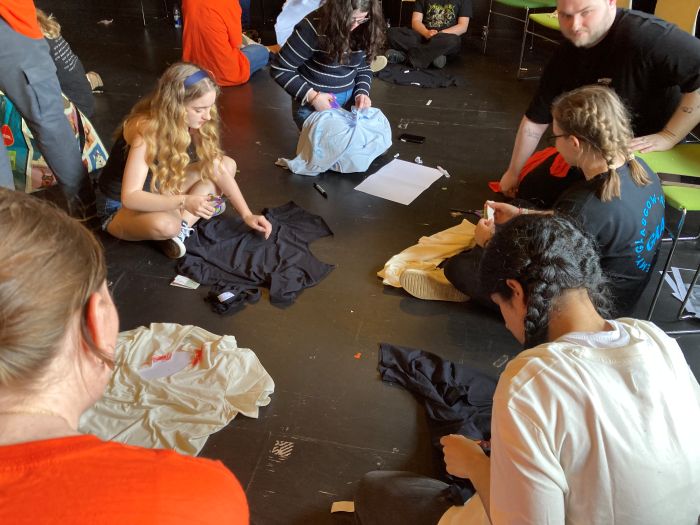 a group of young people sitting on the ground altering t shirts