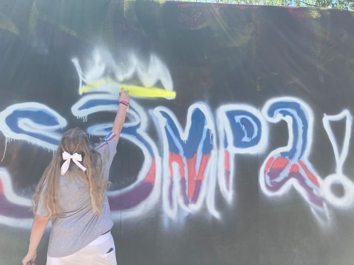 A young person spray painting a wall