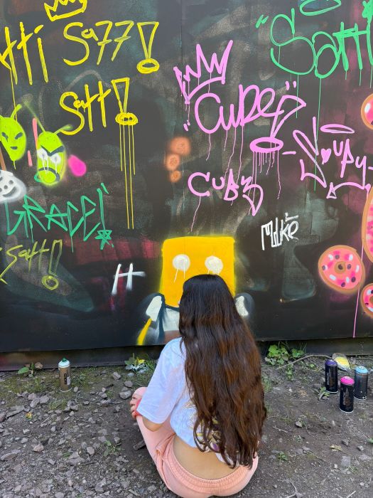 A young person spray painting a wall