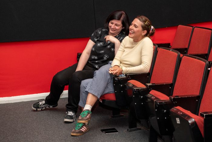 Two people sitting in cinema chairs laughing