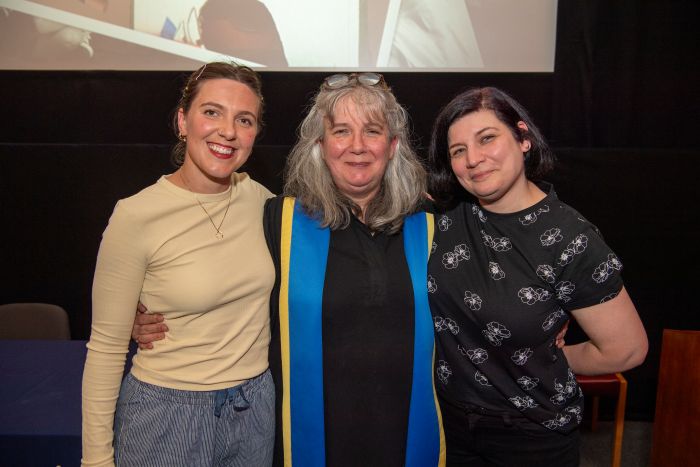 Three people standing together smiling and looking at the camera