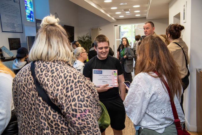A young person showing two people his certificate