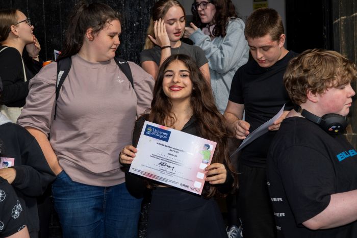 A young person shows her certificate to the camera