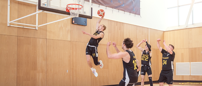 Mens Basketball team cheering on player slam dunking into net