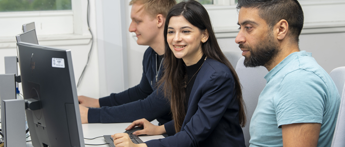 Three students using desktop computers
