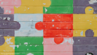 A photo of a wall with jigsaw pieces in bright colours painted on it