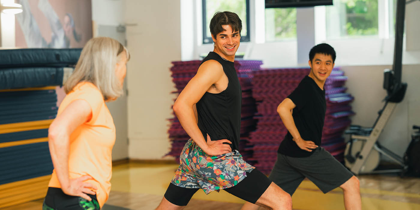 Three people talking whilst taking part in a yoga class