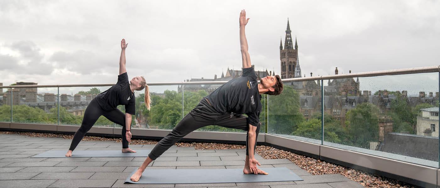 Students posing in yoga positions on the JMS Building balcony