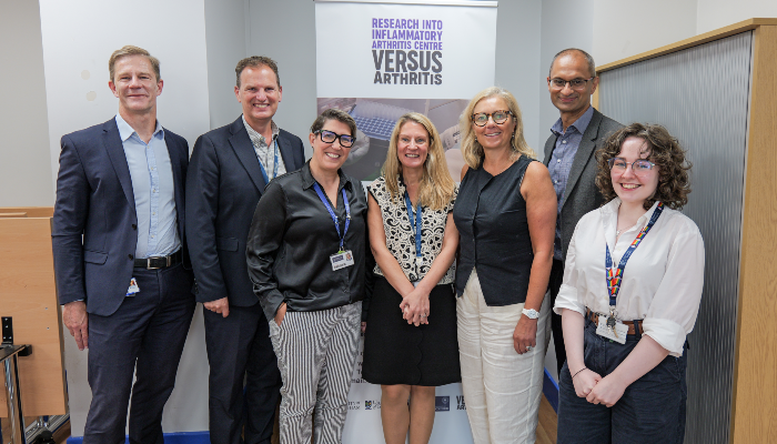 Staff stood with Rachael Hamilton in front of a Versus Arthritis pull-up banner. From left to right: Stefan Siebert, Iain McInnes, Carmen Huesa, Eve Smith, Rachael Hamilton MSP, Neil Basu, and Hope Conway-Gebbie.