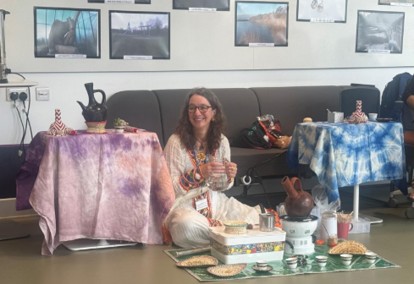 A woman is sitting on the floor in Byres Hub with coffee laid out on a rug in front of her