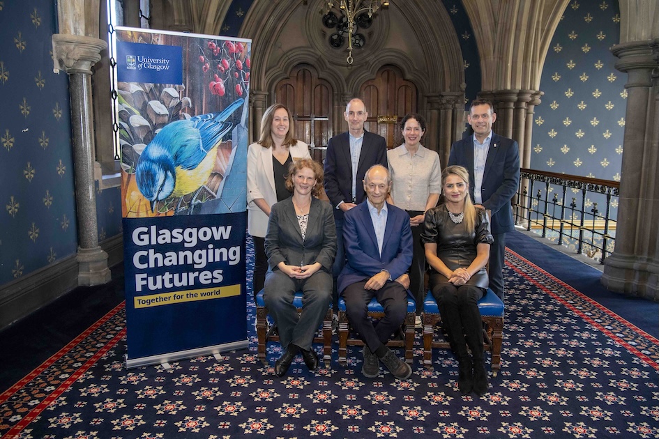 A group of people in two rows, four people standing, three sitting in front next to Glasgow Changing Futures pull-up banner