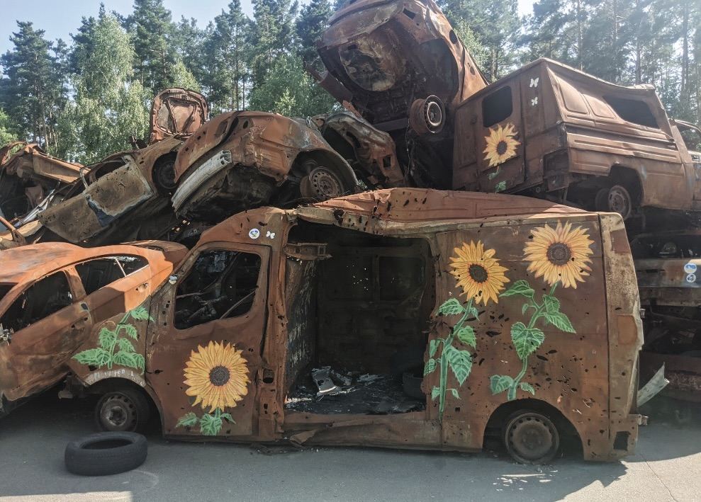 ‘car graveyard’ in Irpin, Ukraine. A stack of burned and rusted vehicles adorned with sunflower artwork. Photo by Alisa Demina (see link to JCA paper)