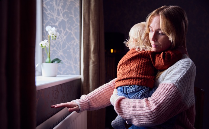 woman holding baby testing heat from radiator