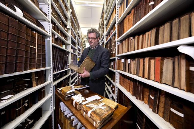 Professor Adrian Streete looking at a book from the personal library of Zachary Boyd held in the University’s Archives & Special Collections. Credit Martin Shields.