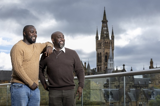 Two men standing on an outdoor platform overlooking the University of Glasgow's main campus