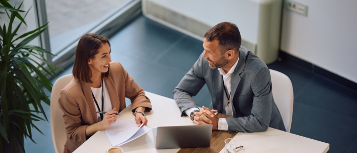 High angle view of happy entrepreneur and her colleague talking during business meeting in the office. Copy space.