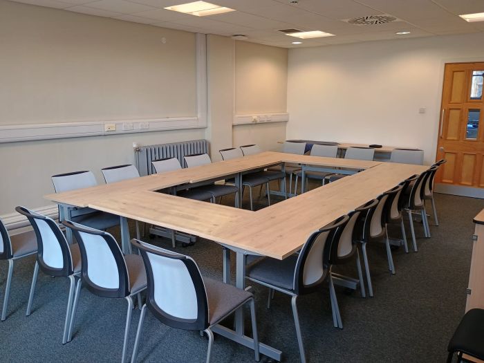 Flat floored meeting room with boardroom tables and chairs.