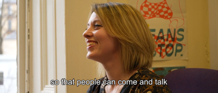 A woman in conversation smiling, a caption below her face reads 