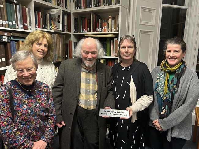 A group of people look into the camera with one of them holding a sign which says Dr John Corley Richards History of Art Resource Centre