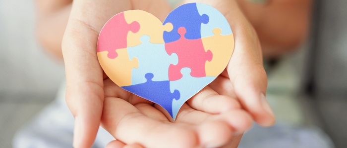 A heart shape made up of jigsaw pieces being cupped in two hands