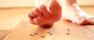 foot stepping on tacks