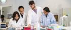 a lecturer and students gathered around a desk in a lab
