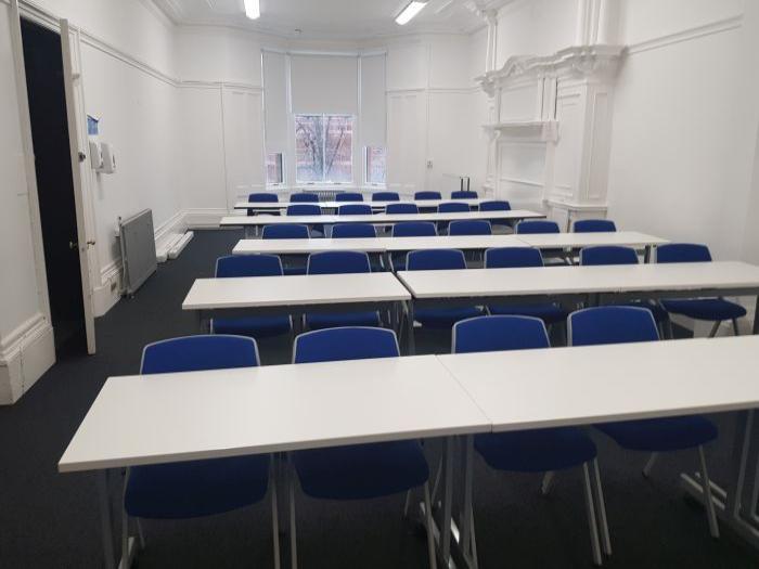 Flat floored teaching room with rows of tables and chairs