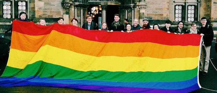 Image of UofG people holding the LGBT+ flag
