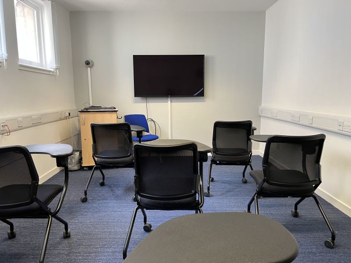 Flat floored teaching room with tablet chairs, video monitor, and lecturer's chair.