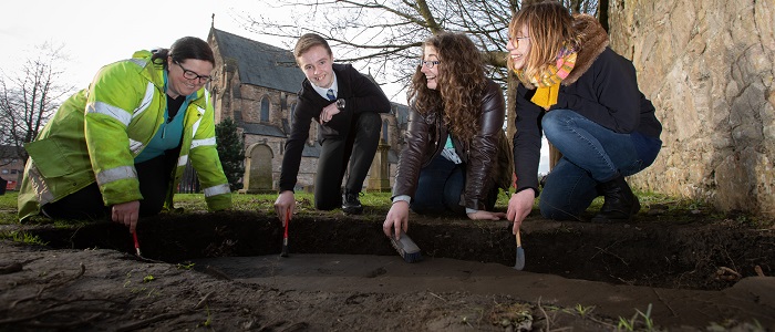 Nicola Reid, Field Archaeolgist, Northlight Heritage; Mark McGettigan, aged 14; Megan Kasten, Project Office & Volunteer, Northlight Heritage and Ingrid Shearer, Community Engagement Officer for Stones & Bones excavation, Northlight Heritage examining one of the three Govan Stones rediscovered at Govan Old Parish Church. 700 x 300 