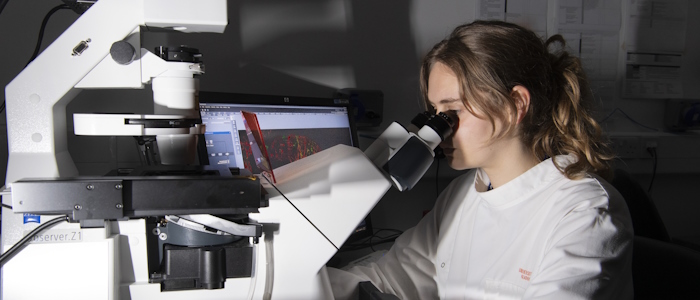 A Wolfson Wohl lab worker looks through a microscope