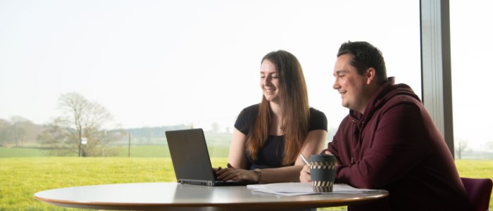 Male and female student working on laptop with great view