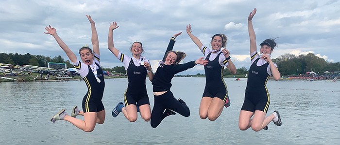 Five Glasgow University Boat Club members jumping at the edge of a pier