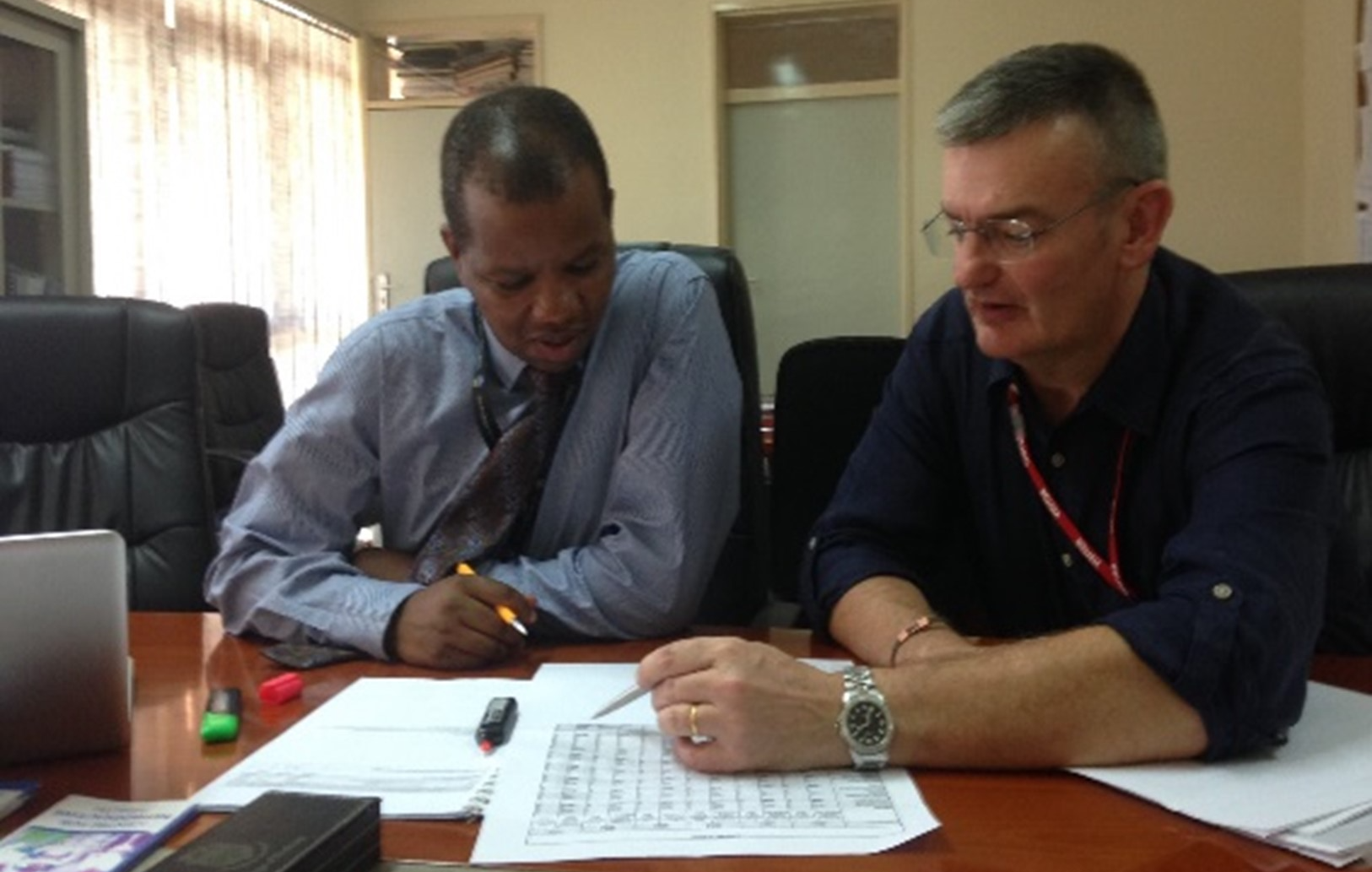 Dr Mipando and Prof Garside sat at a desk poring over the same paper as they working together