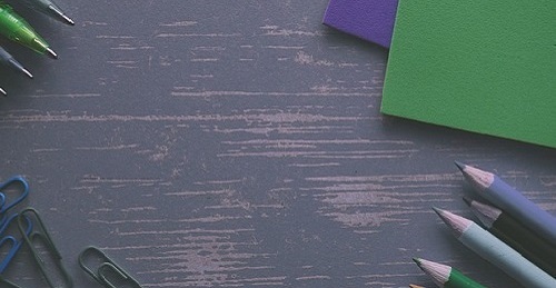 Coloured pencils and paper on a wood grain desk