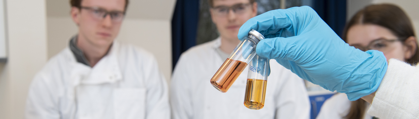 Lab - hand holding chemicals - 1400x400 - splash