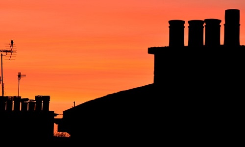 Silhouette of roofline against an orange sky