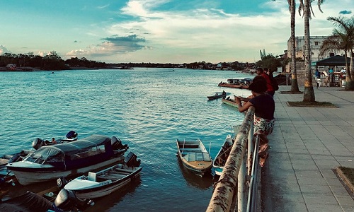 View of river and promenade running alongside with a few boats and figures