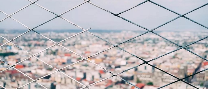 Blurry view of city in the distance through a diamond mesh fence
