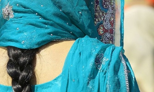 Back view of an Indian woman with her black hair in a plait and wearing in a light blue outfit and scarf over her head. Image credit: ChiccoDodiFC | iStockphoto https://www.istockphoto.com/photo/woman-with-dress-and-long-black-hair-gm954544102-260615928