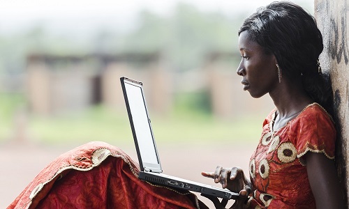 A young African woman sitting and leaning against a wall to use her laptop.Image credit: borgogniels | iStockphoto https://www.istockphoto.com/photo/technology-symbol-african-woman-studying-learning-lesson-gm529835071-54284780