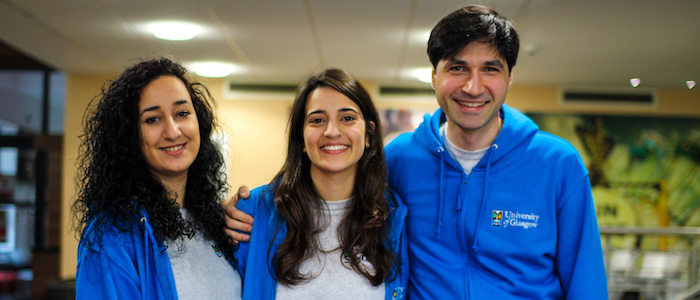 Three Residence Life Assistants wearing blue hoodies and grey t-shirts smiling