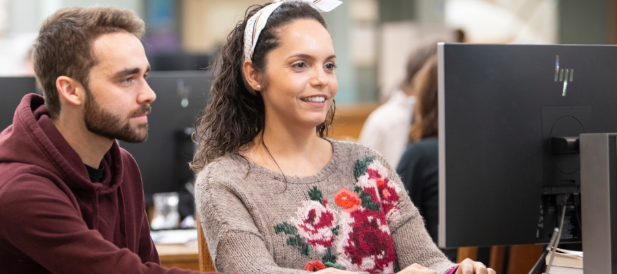 Students smiling at a shared computer