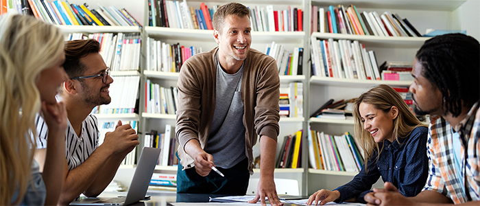 Teacher presenting in front of group of students at desk