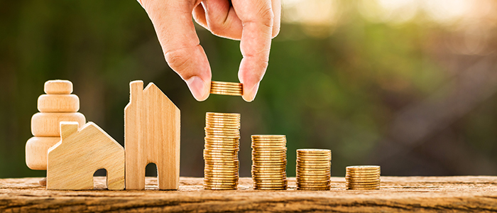 Coins lined up with small wooden houses beside it